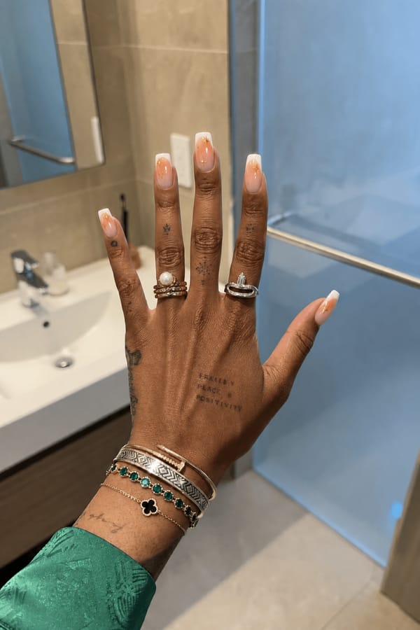 Nude nails with an orange aura and white French tips