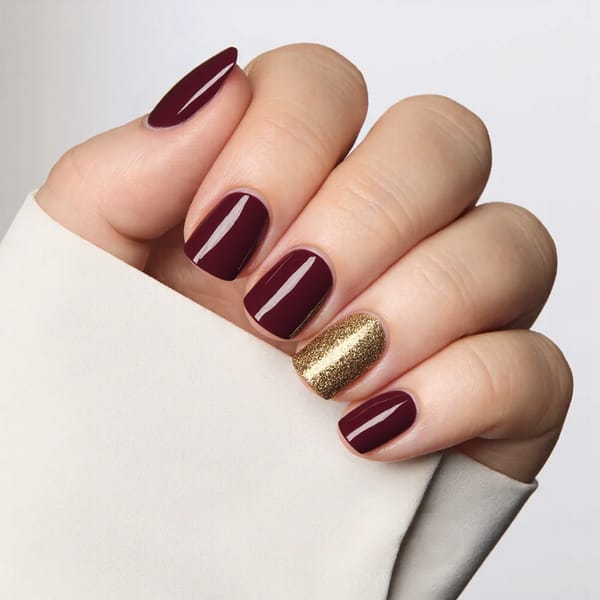Short square nails in rich maroon with a single gold glitter accent nail for a pop of fall glam.