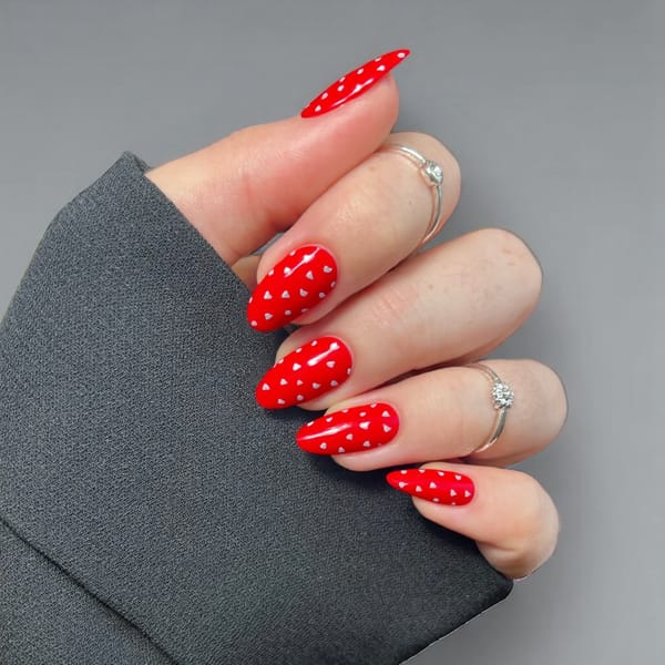 Short almond nails in a romantic red with tiny silver hearts for a perfect Valentine's Day look.