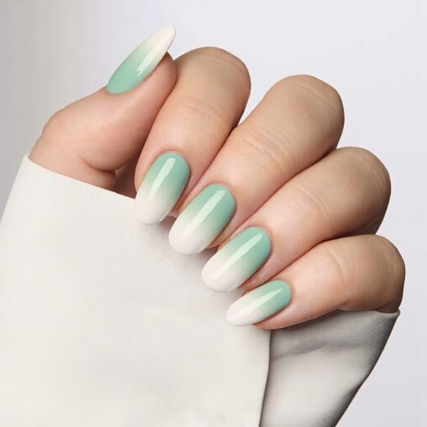 Medium almond nails in a gradient ombre from pastel green to white, ideal for a spring-inspired manicure.