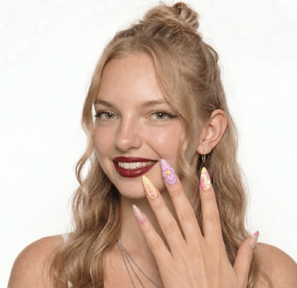 Mixed pastel design with glossy finish. 5 accent nails: Soft yellow base with vertical pink dots along one side. Pink-lilac base with a large 3D-style flower (yellow center). Nude-pink base with abstract hot pink and yellow swirl. Pale yellow base with pink abstract shapes and small white dots. Nude base with minimal pink dot accents near the tip. Nail shape: stiletto. Nail length: medium. Only change the nails visible in the image to match this design. Keep the rest of the image — the hand, skin, background, lighting, and everything else — exactly the same.