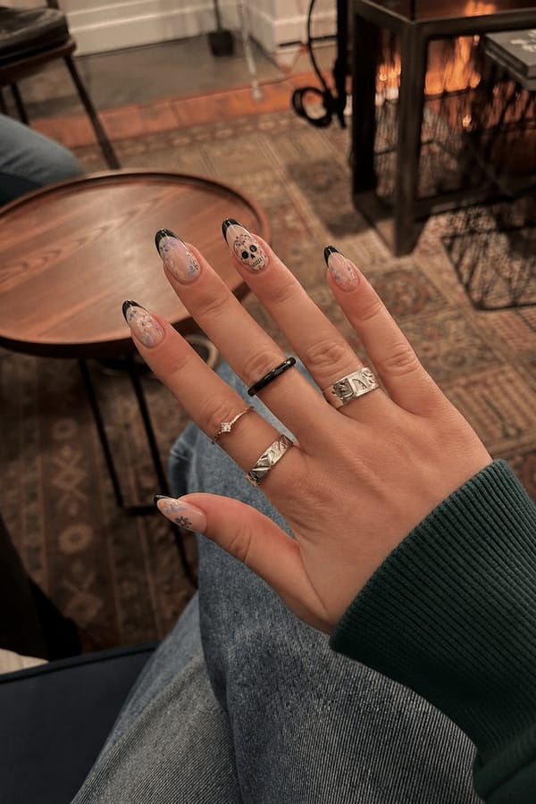 Black French tip Sugar skull Soft pastel abstract art Flowers Nail shape: almond. Nail length: medium. Only change the nails visible in the image to match this design. Keep the rest of the image — the hand, skin, background, lighting, and everything else — exactly the same.