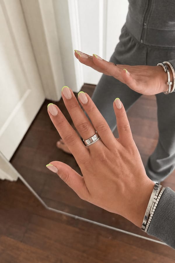 nude base and very thin lime neon green French tip Nail shape: almond. Nail length: short. Only change the nails visible in the image to match this design. Keep the rest of the image — the hand, skin, background, lighting, and everything else — exactly the same.