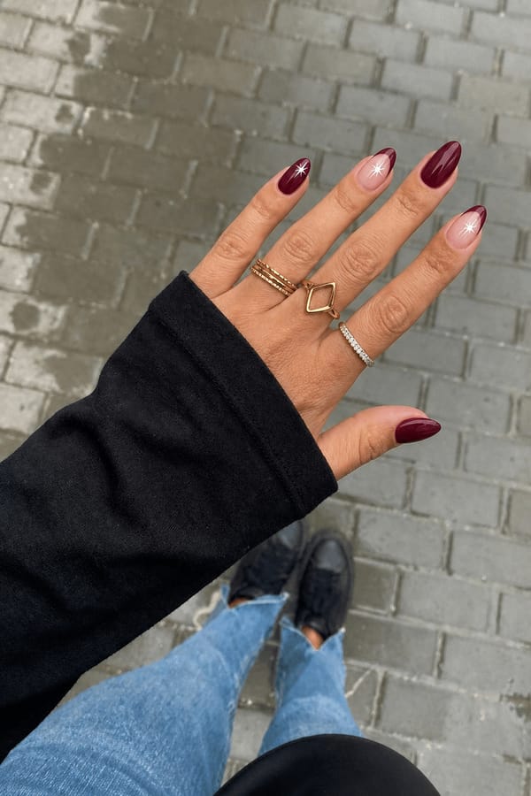 make the thumb, point finger and pinky all wine red. the to other nails are going to have a wine red french with one white star on each Nail shape: almond. Nail length: medium. Only change the nails visible in the image to match this design. Keep the rest of the image — the hand, skin, background, lighting, and everything else — exactly the same.