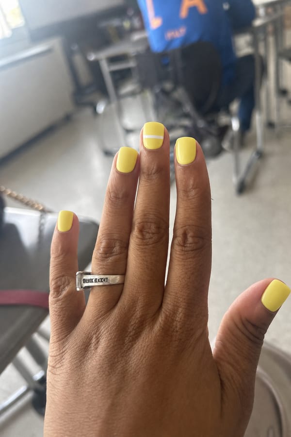 Short square nails in a lemon-yellow shade with a simple white stripe across one accent nail. Nail shape: square. Nail length: short. Only change the nails visible in the image to match this design. Keep the rest of the image — the hand, skin, background, lighting, and everything else — exactly the same.