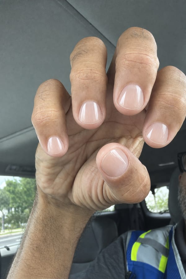 Base nude transparente y brillante en todas las uñas. Bordes pulidos, sin adornos. Acabado natural sutil. Nail shape: round. Nail length: short. Only change the nails visible in the image to match this design. Keep the rest of the image — the hand, skin, background, lighting, and everything else — exactly the same.