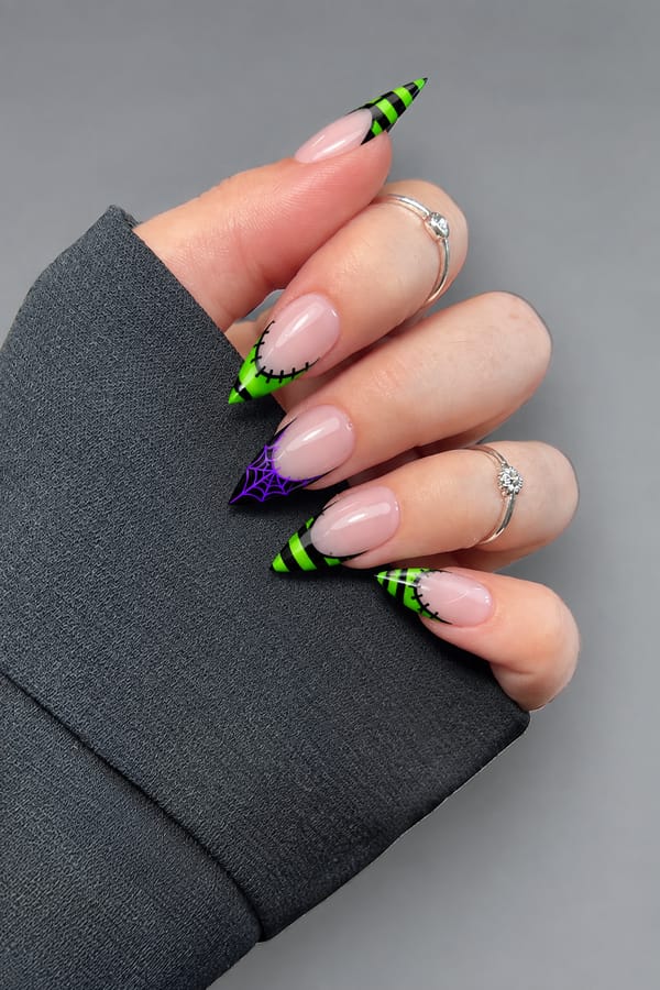 Full French tip nails set, with stitches. the colors used are electric purple , black and neon green.each nail a different design. one or two with green and black horizontal stripes another with green french tip and stitches around curve of French tip. one with a spiderweb. all nails should be French tip Nail shape: stiletto. Nail length: long. Only change the nails visible in the image to match this design. Keep the rest of the image — the hand, skin, background, lighting, and everything else — exactly the same.