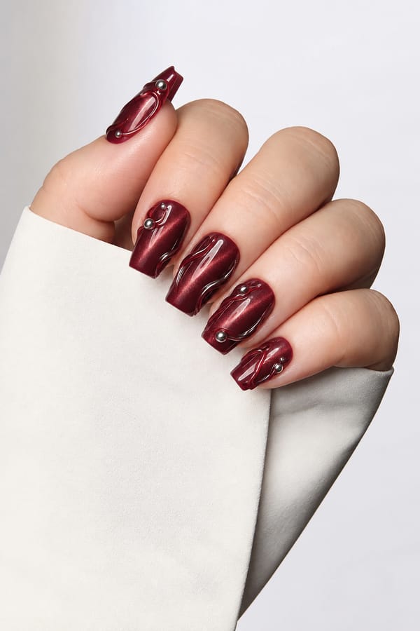 november nails. I like cat eye polish and 3d art. no flowers please Nail shape: square. Nail length: medium. Only change the nails visible in the image to match this design. Keep the rest of the image — the hand, skin, background, lighting, and everything else — exactly the same.