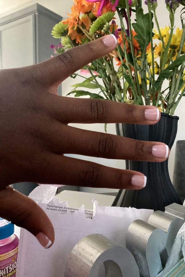 Classic white French tips on a soft pink base for an elegant touch Nail shape: square. Nail length: short. Only change the nails visible in the image to match this design. Keep the rest of the image — the hand, skin, background, lighting, and everything else — exactly the same.