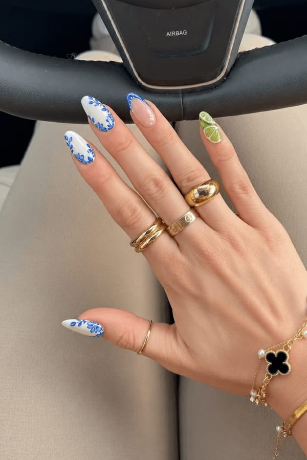 Mixed glossy set, 5 accent nails: 1–2) White base with blue floral/leaf patterns along the edges. 3) Nude base with a blue curved French outline and white dots. 4–5) 3D lime slice designs with translucent green segments and raised texture, placed across the nail surface. Nail shape: almond. Nail length: long. Only change the nails visible in the image to match this design. Keep the rest of the image — the hand, skin, background, lighting, and everything else — exactly the same.