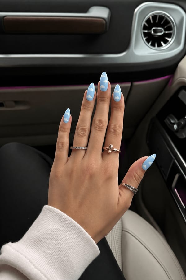 Powder blue almond nails featuring hand-painted clouds