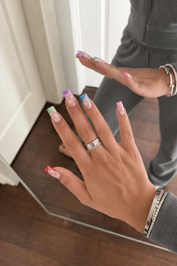 long nails and each nail a different color with red, green, purple ,blue, pink French tip and small white flowers all over the top Nail shape: square. Nail length: long. Only change the nails visible in the image to match this design. Keep the rest of the image — the hand, skin, background, lighting, and everything else — exactly the same.