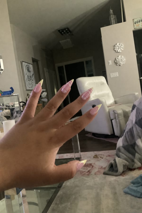pink plaid on three nails on hand Bose on plaid three hands pastel yellow French tips ￼. Nail shape: stiletto. Nail length: extra_long. Only change the nails visible in the image to match this design. Keep the rest of the image — the hand, skin, background, lighting, and everything else — exactly the same.