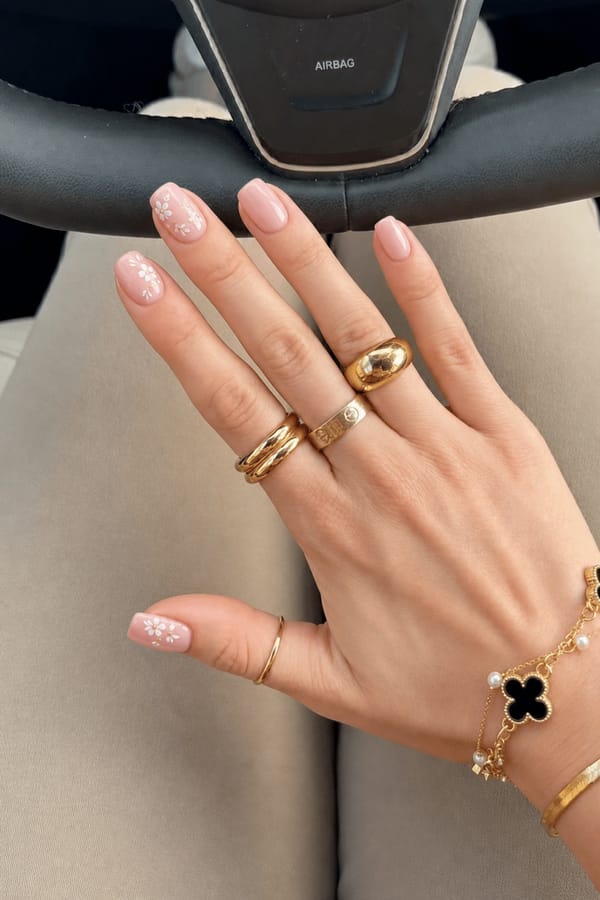I'm attending a summer wedding, and I want a romantic look with soft pink tones and delicate white floral accents. Could you design something elegant and subtle? Nail shape: square. Nail length: short. Only change the nails visible in the image to match this design. Keep the rest of the image — the hand, skin, background, lighting, and everything else — exactly the same.