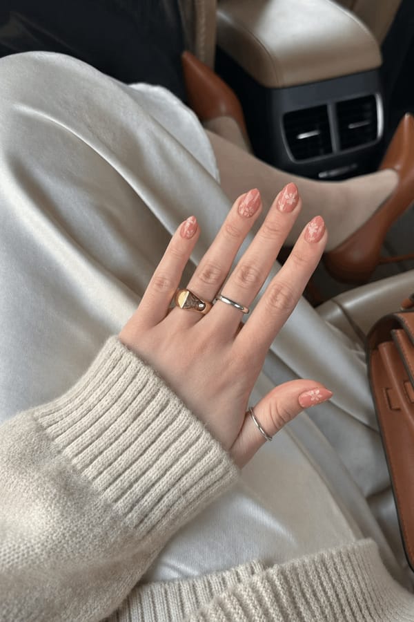 Muted coral nails with translucent floral overlays