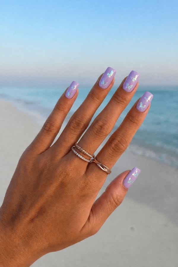 Lavender stiletto nails adorned with iridescent butterfly stickers