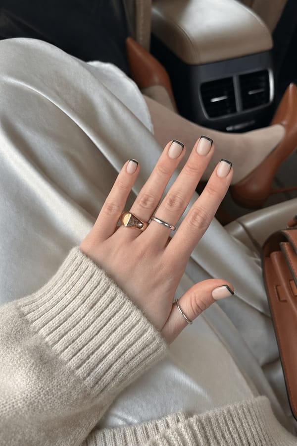 Black French tips with a matte finish over a creamy nude background