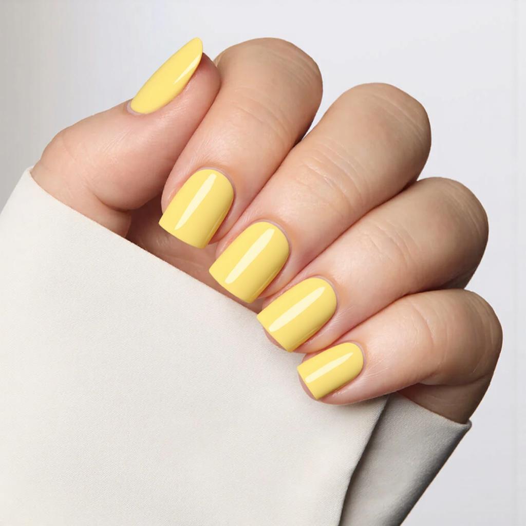 Short square nails in a lemon-yellow shade with a simple white stripe across one accent nail.