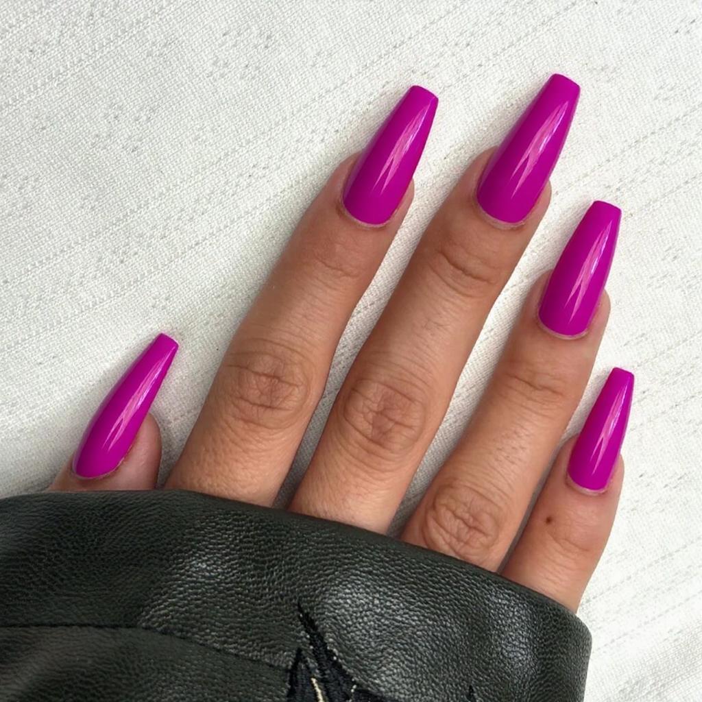 Long stiletto nails in a vibrant fuchsia, adding a glossy topcoat for a fierce, eye-catching finish.