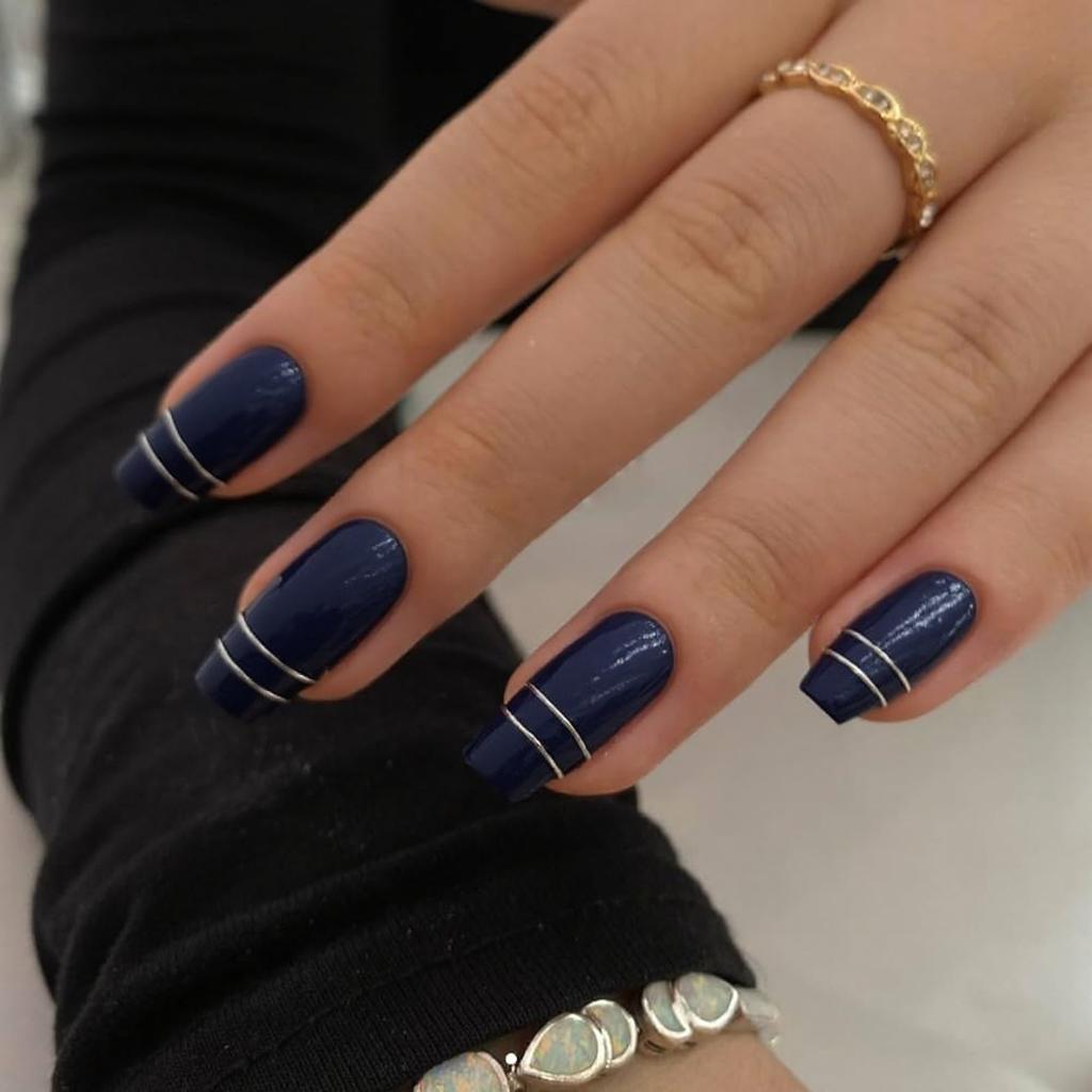 Short stiletto nails in a deep sapphire color, plus a thin silver line framing one accent nail.