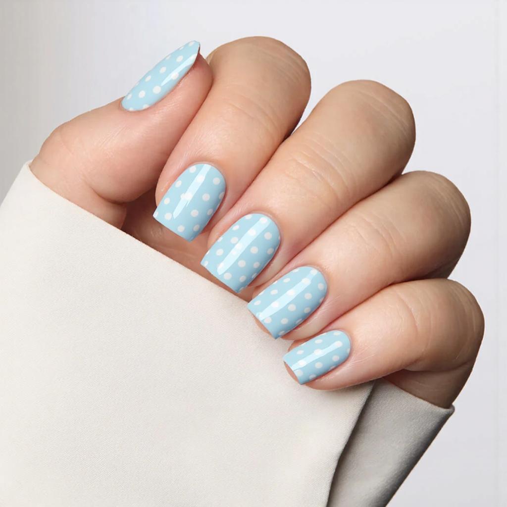 Short square nails with a soft pastel blue base and minimal white polka dots for a playful touch.