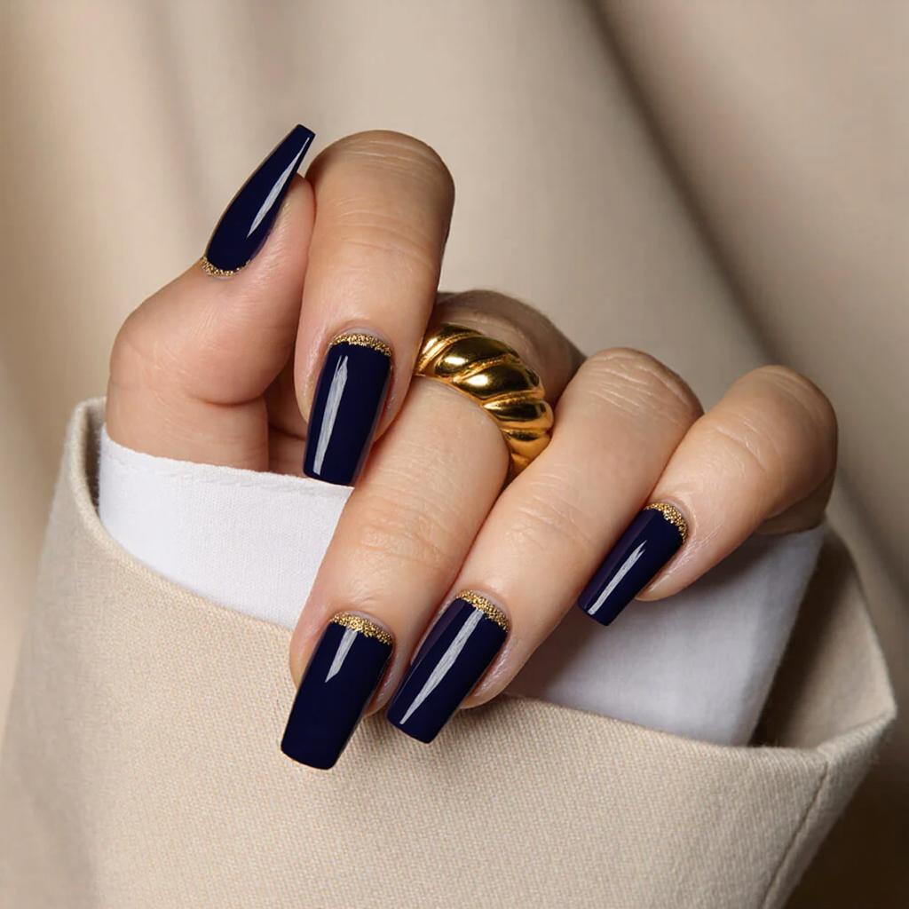 Medium square nails in a deep navy blue, with a thin gold glitter line along each tip.