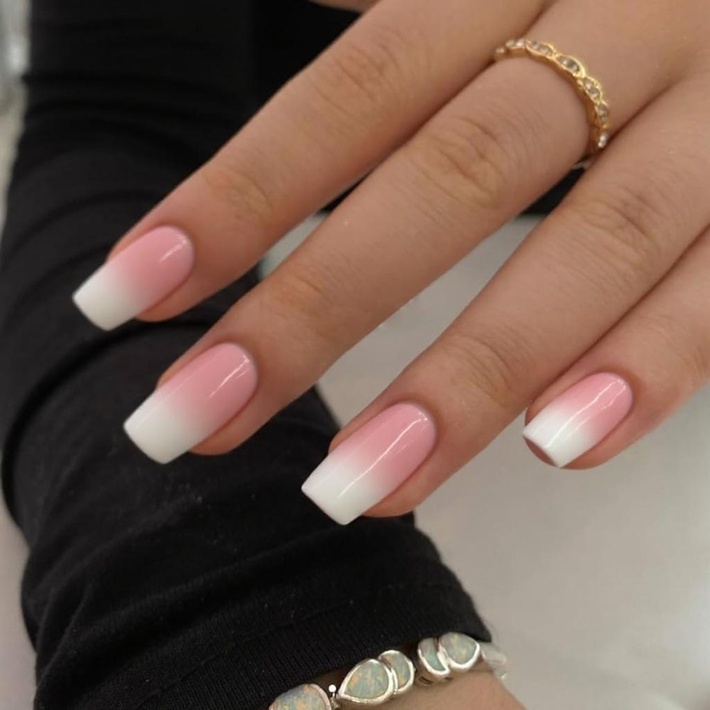 Short stiletto nails in a French ombre design, blending pink into white for a subtle gradient.