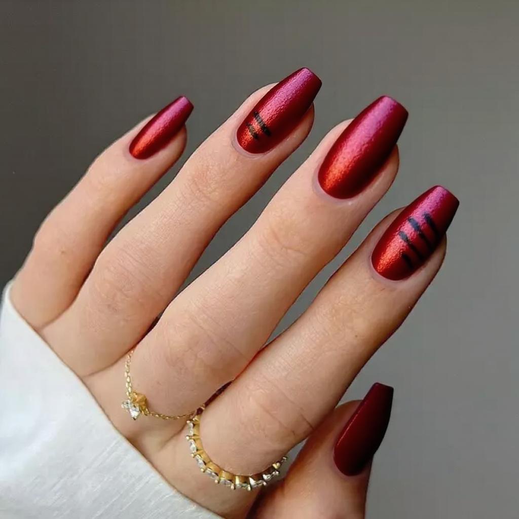 Medium stiletto nails in a cherry-red metallic finish, adding a single black stripe on each ring finger.