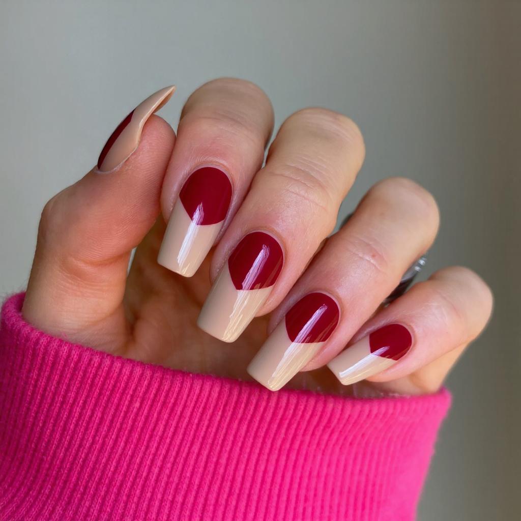 Long square nails with a deep French tip in a bold red, contrasting with a sheer nude base.