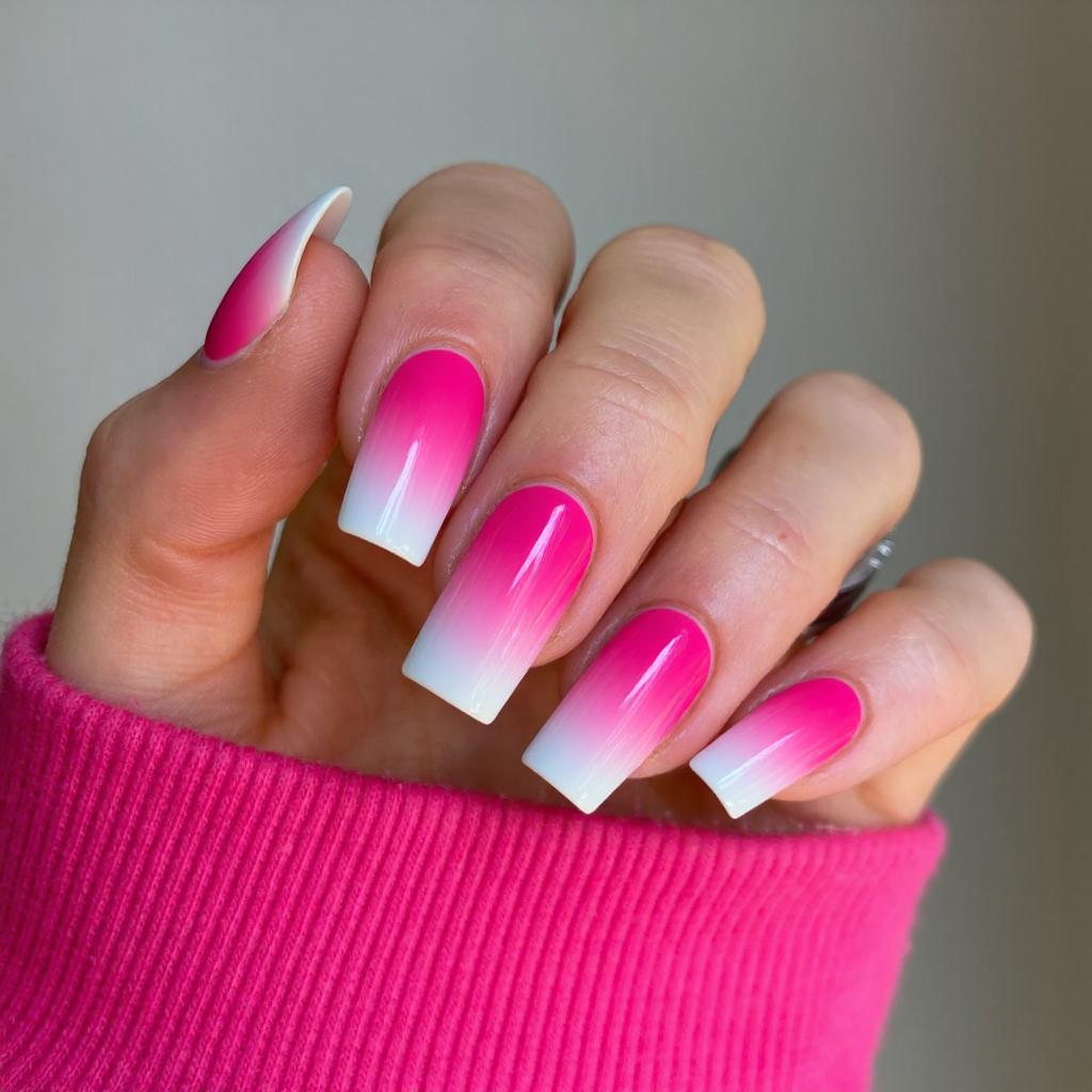 Long square nails in a bold French tip style: bright pink tips with a clear base to show off the design.