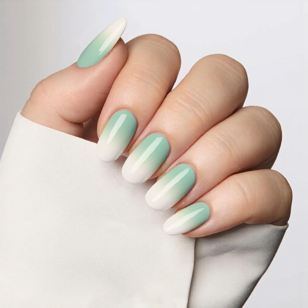 Medium almond nails in a gradient ombre from pastel green to white, ideal for a spring-inspired manicure.