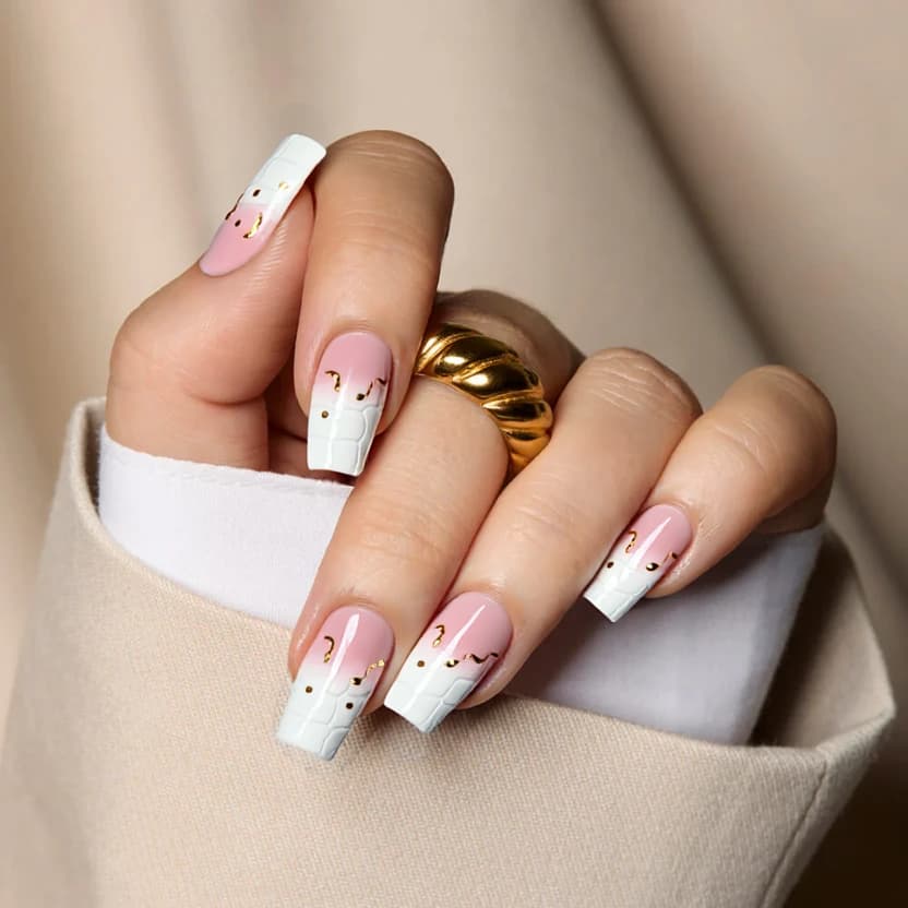 Nails painted in a soft pink base color, creating a feminine and elegant look. The pink shade forms a smooth canvas for the accent nails: the pinky and index fingers adorned with a textured crocodile effect in white, providing a subtle yet striking contrast. The middle and ring fingers feature a classic French manicure transitioning from pure white at the tips to a delicate pink, embellished with gentle wave patterns and small gold dots gently positioned near the base to add a hint of glamour. The thumb showcases a white crocodile effect on a pink base, similarly topped with a gold dot for continuity and cohesion in the design. The glossy finish enhances the overall aesthetic, harmoniously blending the textural elements with the refined color palette, tailored perfectly for the square shape of the medium nails.