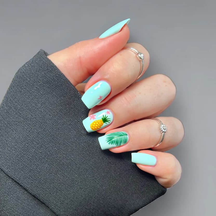 A vibrant tropical-themed nail design perfect for a beach vacation. The nails feature a soft pastel turquoise base color on all nails, creating a gentle oceanic feel. On the ring fingers, there's a delicate pattern of hand-painted palm leaves in a muted green, accompanied by small, minimalist hibiscus flowers in soft pink. The accent nails also showcase subtle, stylized pineapples in a pastel yellow, keeping the overall look light and fun. The remaining nails are kept plain with the same turquoise polish to enhance the elegance of the design. A glossy finish adds a fresh, beachy vibe, ideal for the joyful spirit of a tropical getaway.