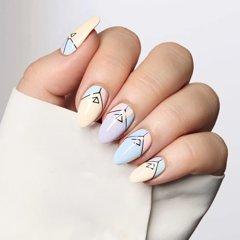 Almond-shaped nails featuring a soft, creamy base color that smoothly transitions into a subtle pastel palette. The ring and middle fingers are adorned with minimal geometric patterns, showcasing delicate triangles and soft lines in light blue, blush pink, and lavender shades. These shapes are thoughtfully arranged to create a balanced effect, with no more than four elements on each of the accented nails, ensuring an elegant and harmonious look. The remaining nails are kept simple with the same creamy base color, creating a serene and cohesive design. A glossy finish enhances the overall femininity and is perfect for the graceful curves of medium almond nails.
