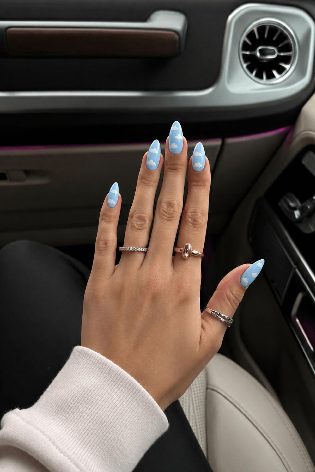 Powder blue almond nails featuring hand-painted clouds