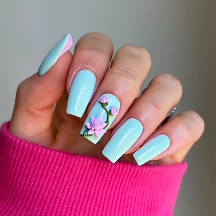 Long square-shaped nails featuring a delicate, ethereal color palette of soft pastel blues and aquamarine, reminiscent of serene water. The base color is applied uniformly across most nails, providing a calm backdrop. On the ring and middle fingers, a minimal yet intricate 3D lotus flower is elegantly placed at the cuticles, crafted in shades of pale pink with subtle shimmers that catch the light. Accompanying the lotus, dainty, stylized roses in soft lavender are positioned around, each adorned with a hint of iridescent sparkle to enhance their lifelike appearance. The finish is a glossy sheen that complements the water theme, ensuring the entire look is feminine, harmonious, and visually striking against the elongated square shape.