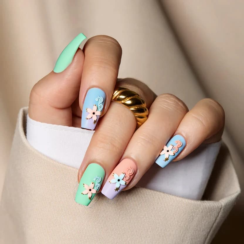 Nails feature a harmonious blend of pastel colors representing the four elements: a soft blue for water, a gentle green for earth, a pale coral for fire, and a light lavender for air. The middle and ring fingers showcase minimal yet striking 3D designs with delicate pastel flowers, swirling clouds, and subtle ocean charms like tiny seashells and starfish. The flowers are arranged in clusters, while the charms are strategically placed to add a touch of dimension without overwhelming the simplistic elegance. The other nails have a solid base color, either in soft green or lavender, creating a cohesive look. A glossy finish enhances the overall design, lending a polished and ethereal feel that complements the medium square shape beautifully.