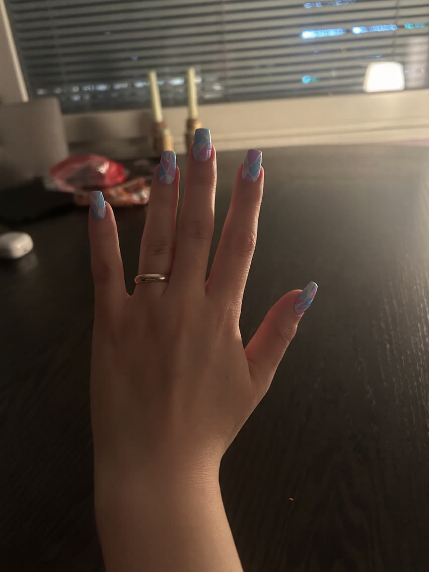 Create a stunning nail art design that features a playful combination of pastel colors in a stiletto shape. Incorporate light blues, soft pinks, and delicate lilacs into a variety of geometric patterns, including sharp triangles, elegant lines, and intriguing shapes that flow seamlessly across the nails. Add a glossy finish to enhance the vibrancy of the colors and consider mixing in some subtle white accents or negative space to create contrast. This design should embody a modern and chic aesthetic, perfect for showcasing a unique style with a light and airy feel.