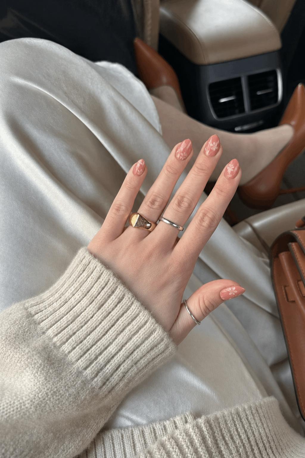 Muted coral nails with translucent floral overlays