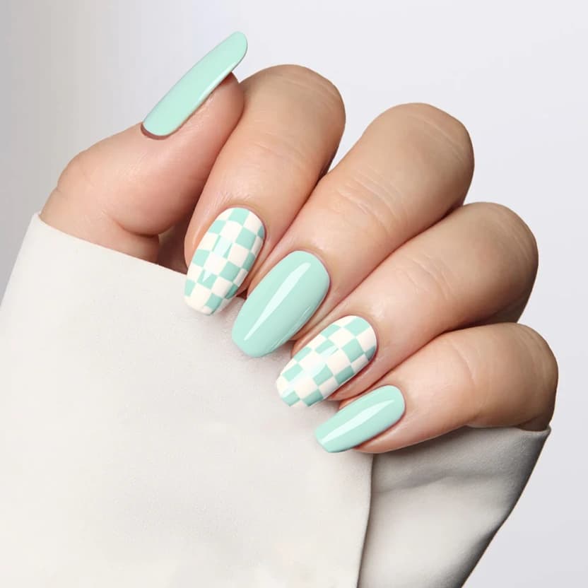 Nails featuring a soft mint gradient that transitions from a darker mint at the cuticle to a lighter shade at the tips, creating a fresh, airy effect ideal for the almond shape. The middle and ring fingers showcase a delicate chessboard pattern, alternating between crisp white and mint squares, with a subtle matte finish for an elegant touch. The gradient base on the remaining fingers complements the playful yet sophisticated chessboard design, while maintaining balance and harmony across the medium-length almond nails.