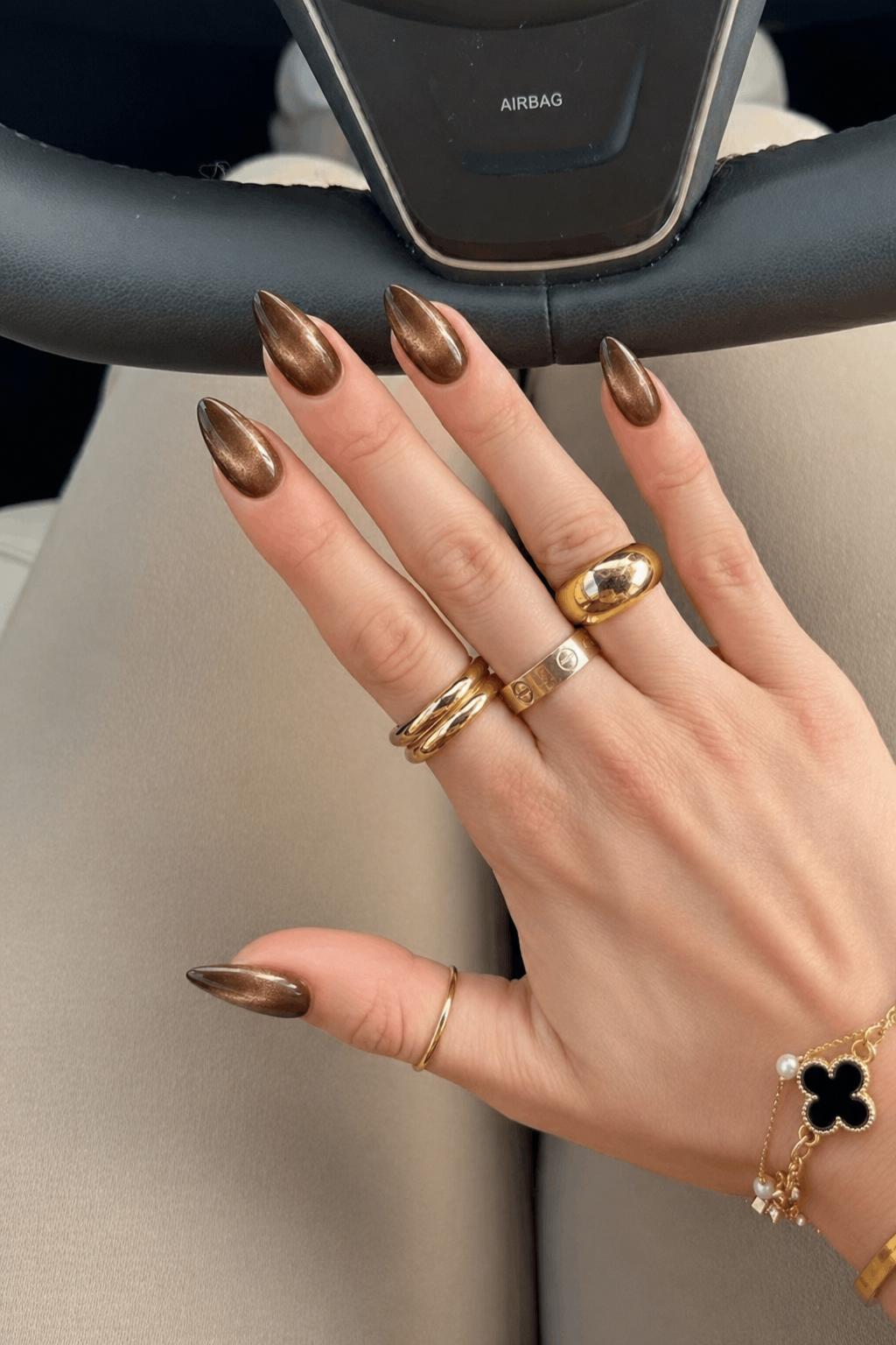 Uniform glossy metallic design with no accent nails (0 accent fingers). All nails feature a deep brown to bronze cat-eye effect with a soft magnetic shimmer concentrated through the center, creating a dimensional reflective stripe. Smooth gradient edges with a glassy finish, no अतिरिक्त patterns or decorations. Nail shape: stiletto. Nail length: medium. Only change the nails visible in the image to match this design. Keep the rest of the image — the hand, skin, background, lighting, and everything else — exactly the same.