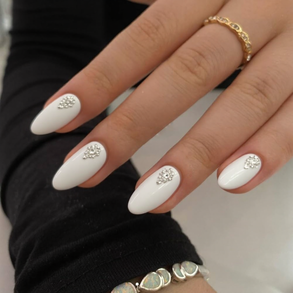 Short stiletto nails in white, each with a tiny rhinestone cluster near the tip for a touch of sparkle.