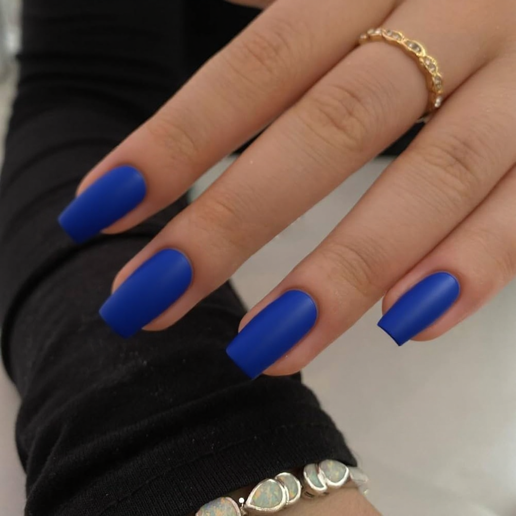 Short stiletto nails in matte royal blue with a single glossy accent nail in the same color.