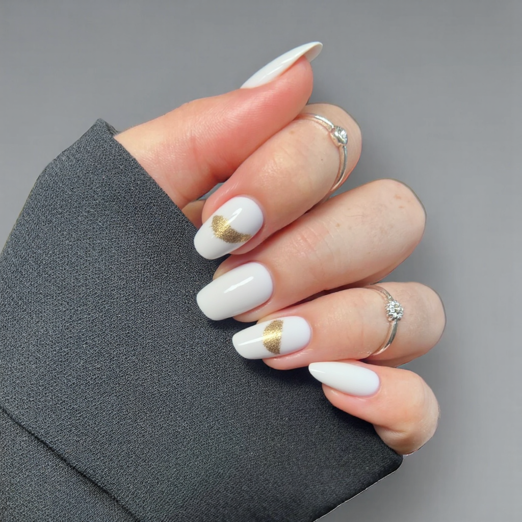 Short almond nails in a cloud-white polish with a soft, brushed-on gold accent near the edges.