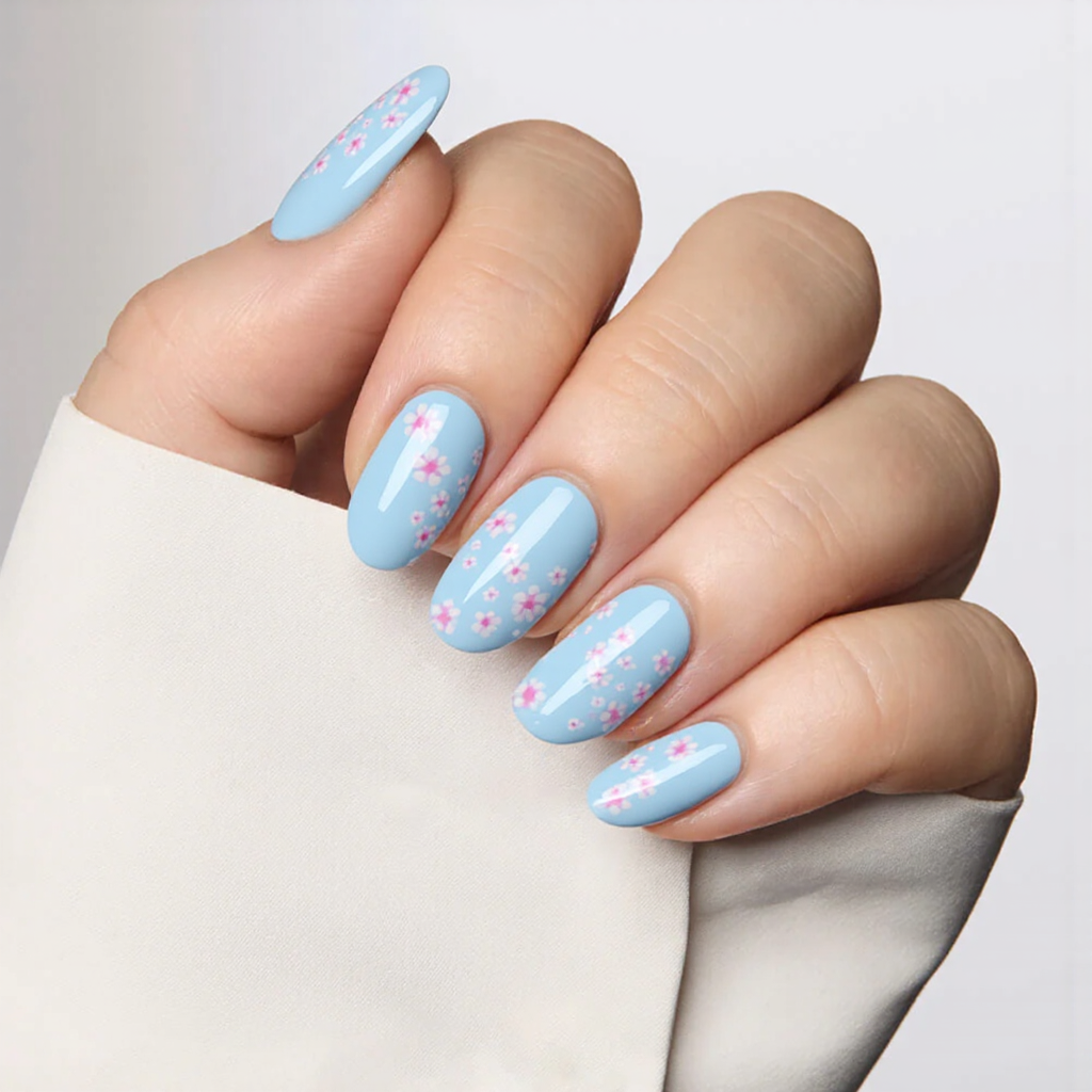 Medium almond nails in sky blue with tiny pink and white flowers for a soft, cute touch.