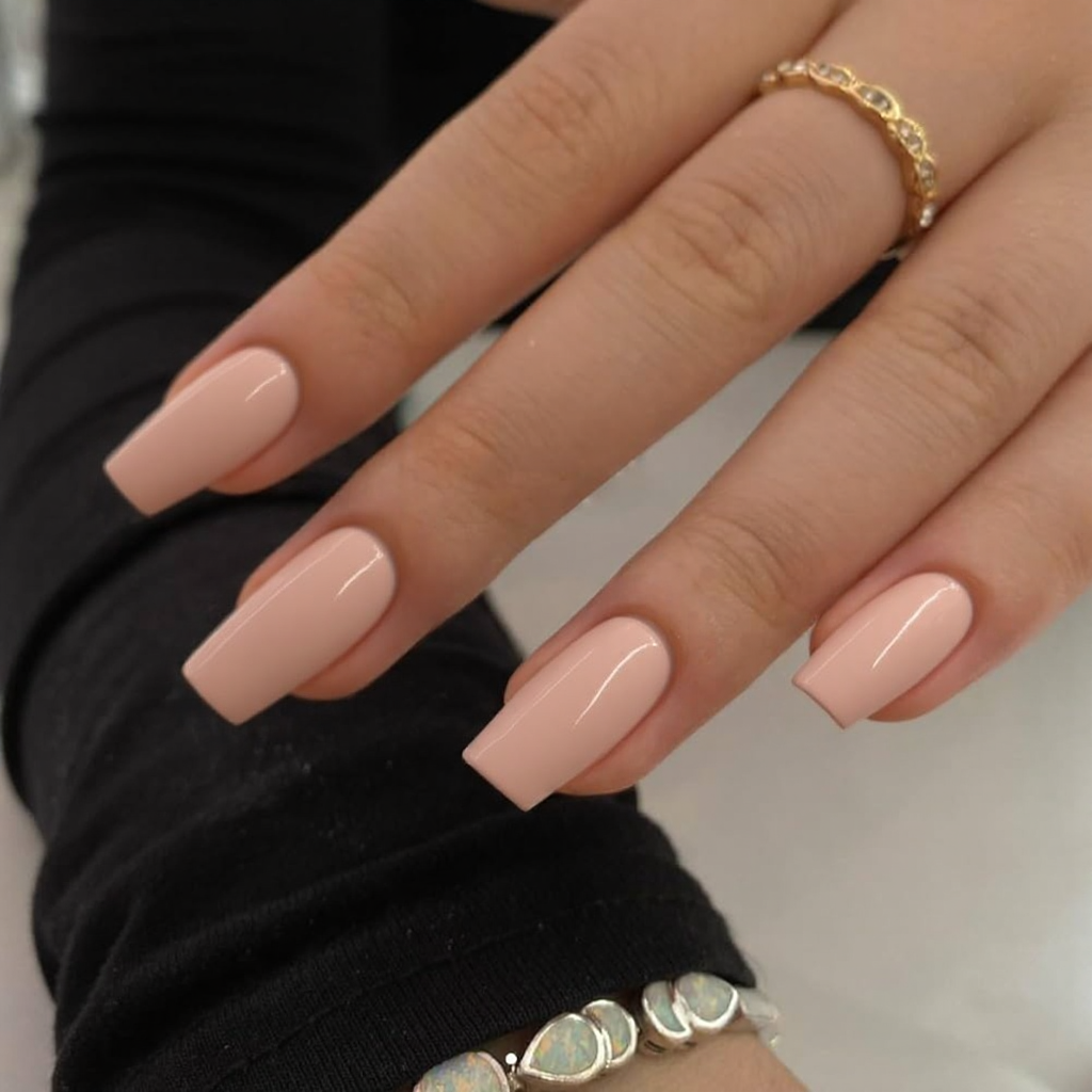Short stiletto nails in a pale peach color, with a subtle shine for a low-maintenance look.