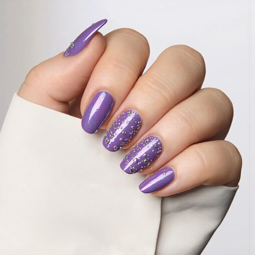 Medium almond nails in a glossy iridescent purple, accented with tiny 3D beads for a standout 2025 look.