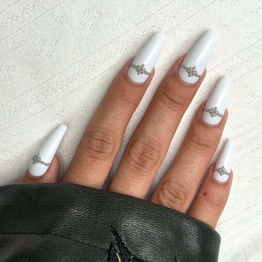 Long stiletto nails in a crisp white French tip, each accent nail adorned with a small rhinestone cluster.