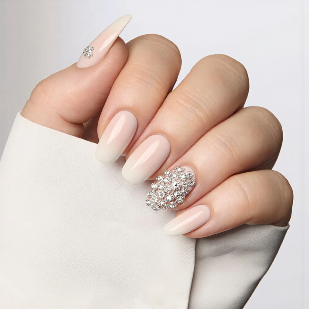 Medium almond nails in a milky-white base, each ring finger adorned with a small rhinestone cluster for wedding sparkle.