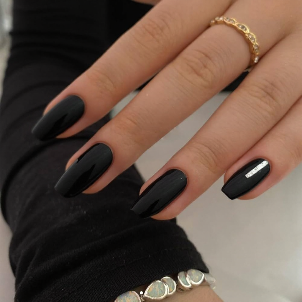 Short stiletto nails in a glossy black with a single silver stripe for a chic and sophisticated January manicure.